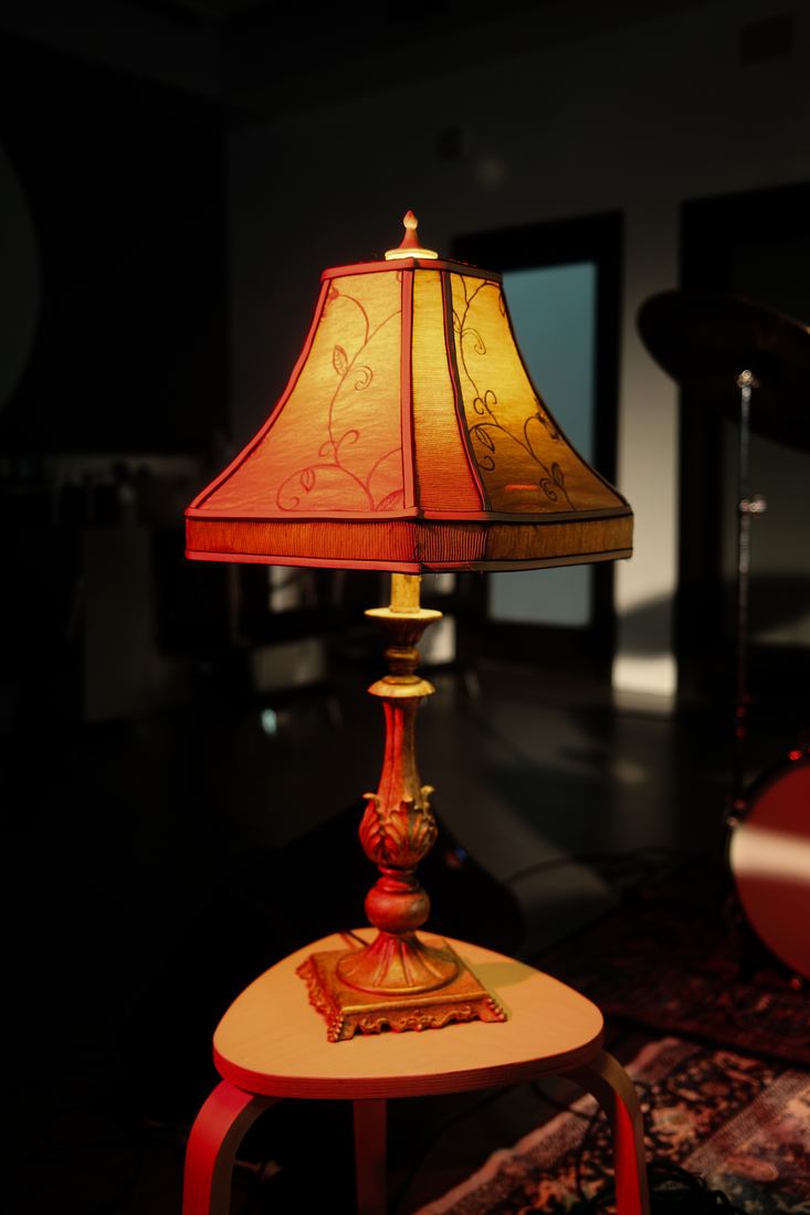 A fringed table lamp glowing in the dark
