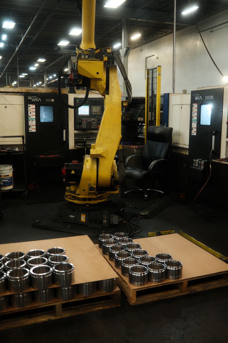 Yellow robotic arm beside CNC machines